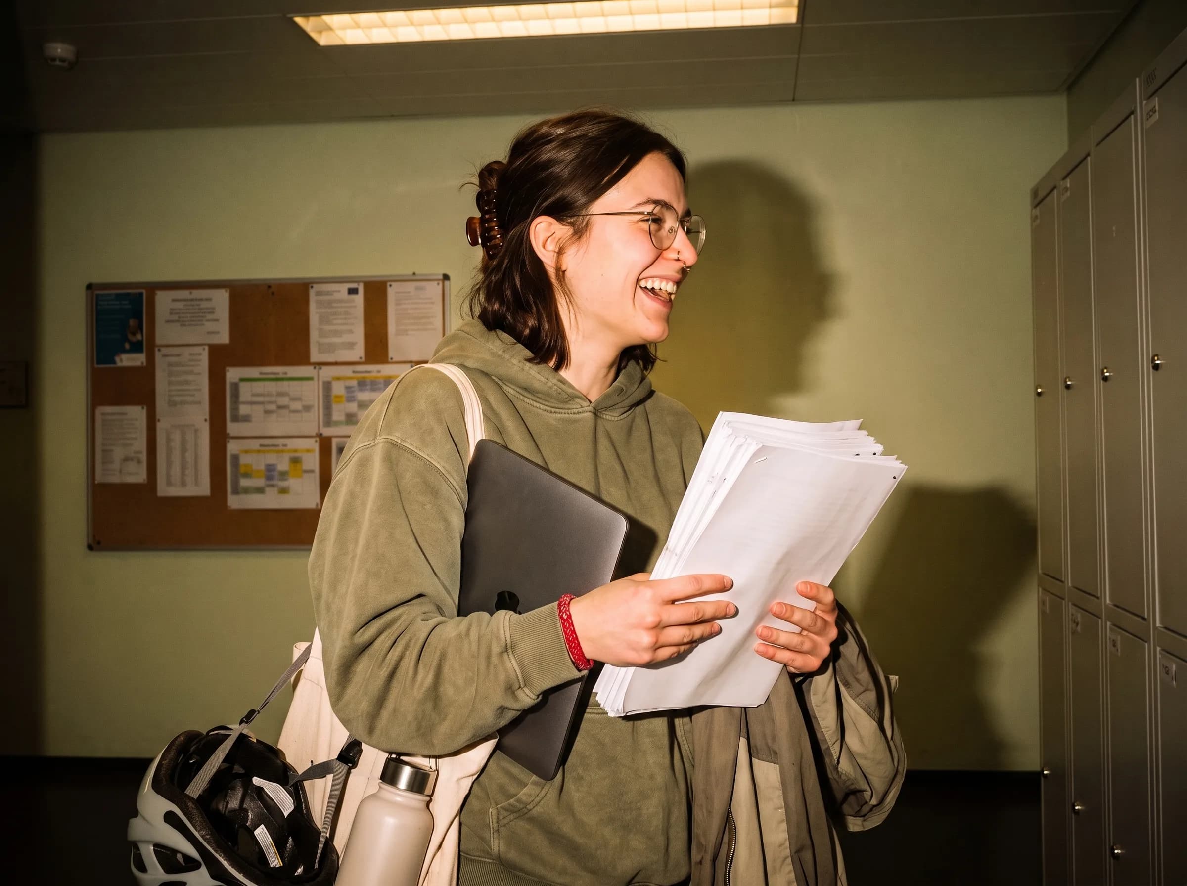 Studentessa che tiene sorridendo il suo elaborato stampato nel corridoio dell'università